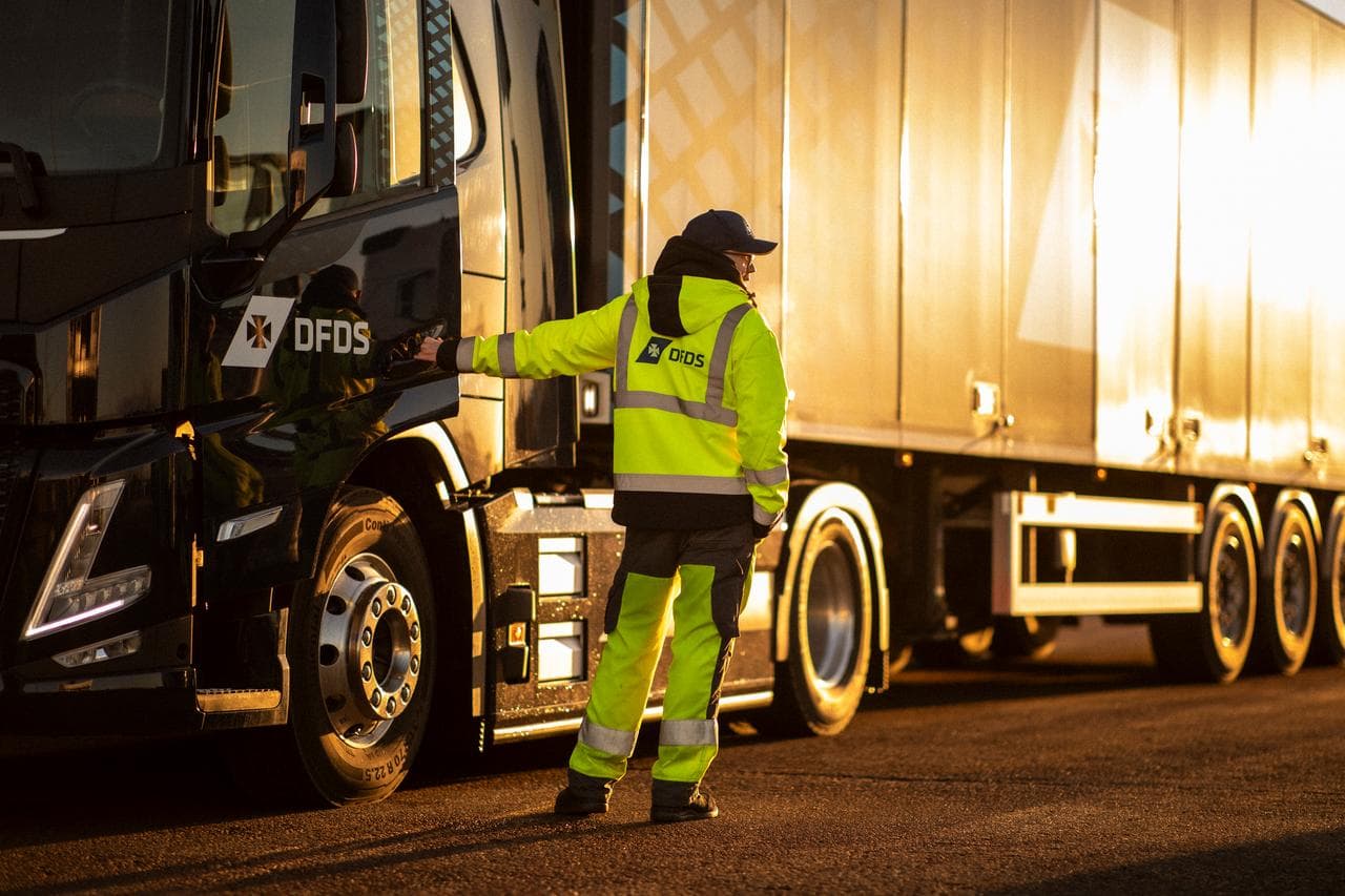 DFDS driver standing next to a DFDS truck, while holding the passenger door open.