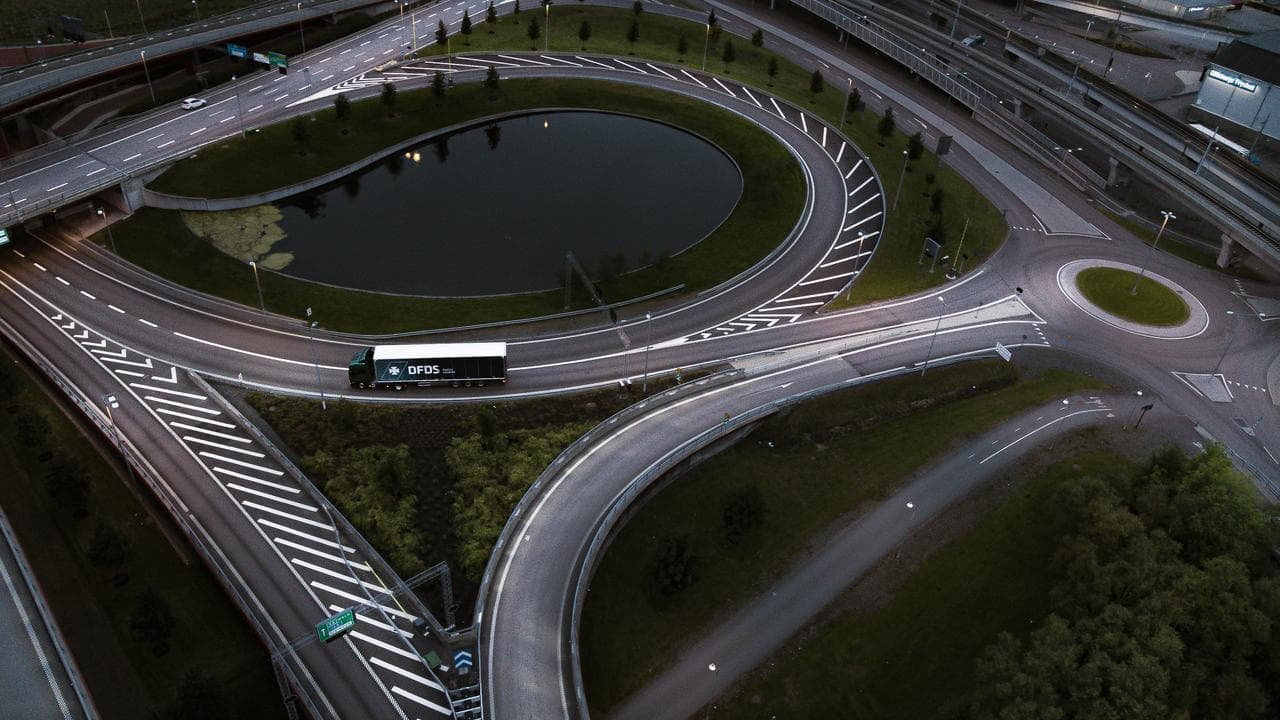 Drone image picture of a roundabout, with only a dark blue truck & trailer of DFDS driving on it