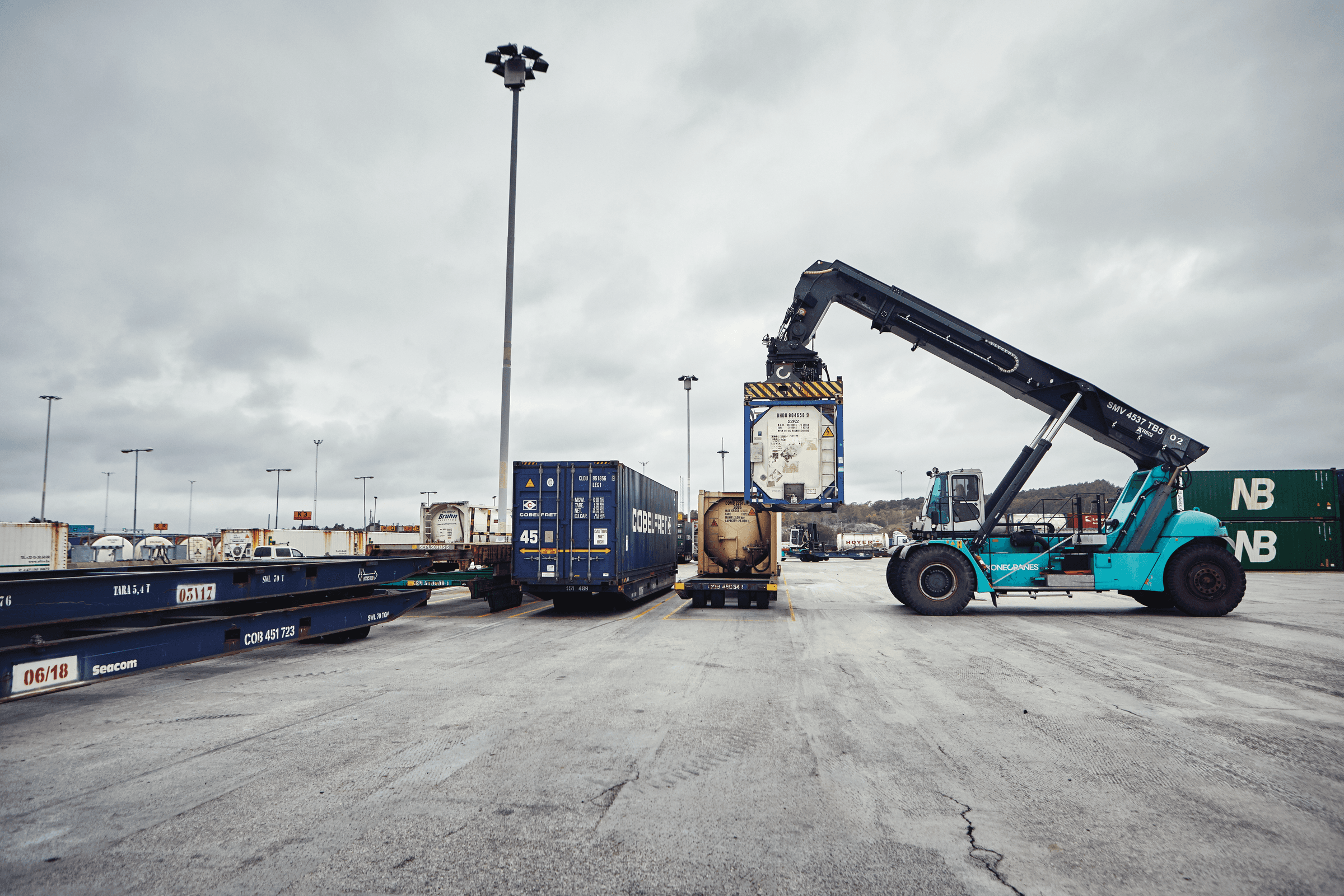 A DFDS Logistics reach stacker lifting a tank at a terminal