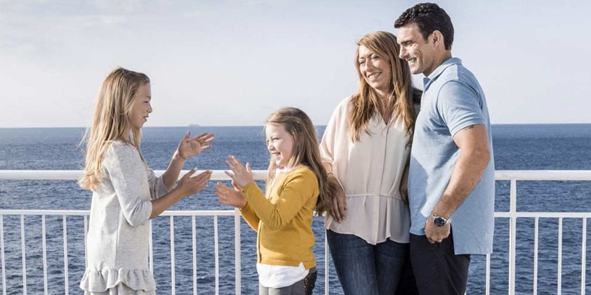 Family on ferry sun deck with two children playing a game