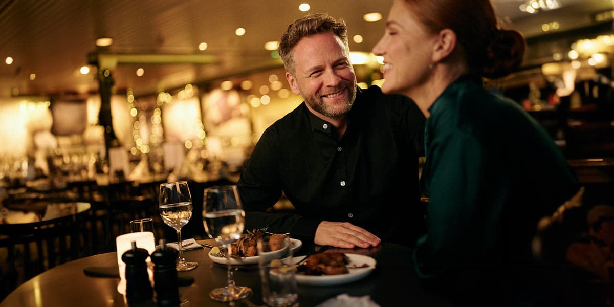 Par i restaurant hygger sig og skåler med et glas vin