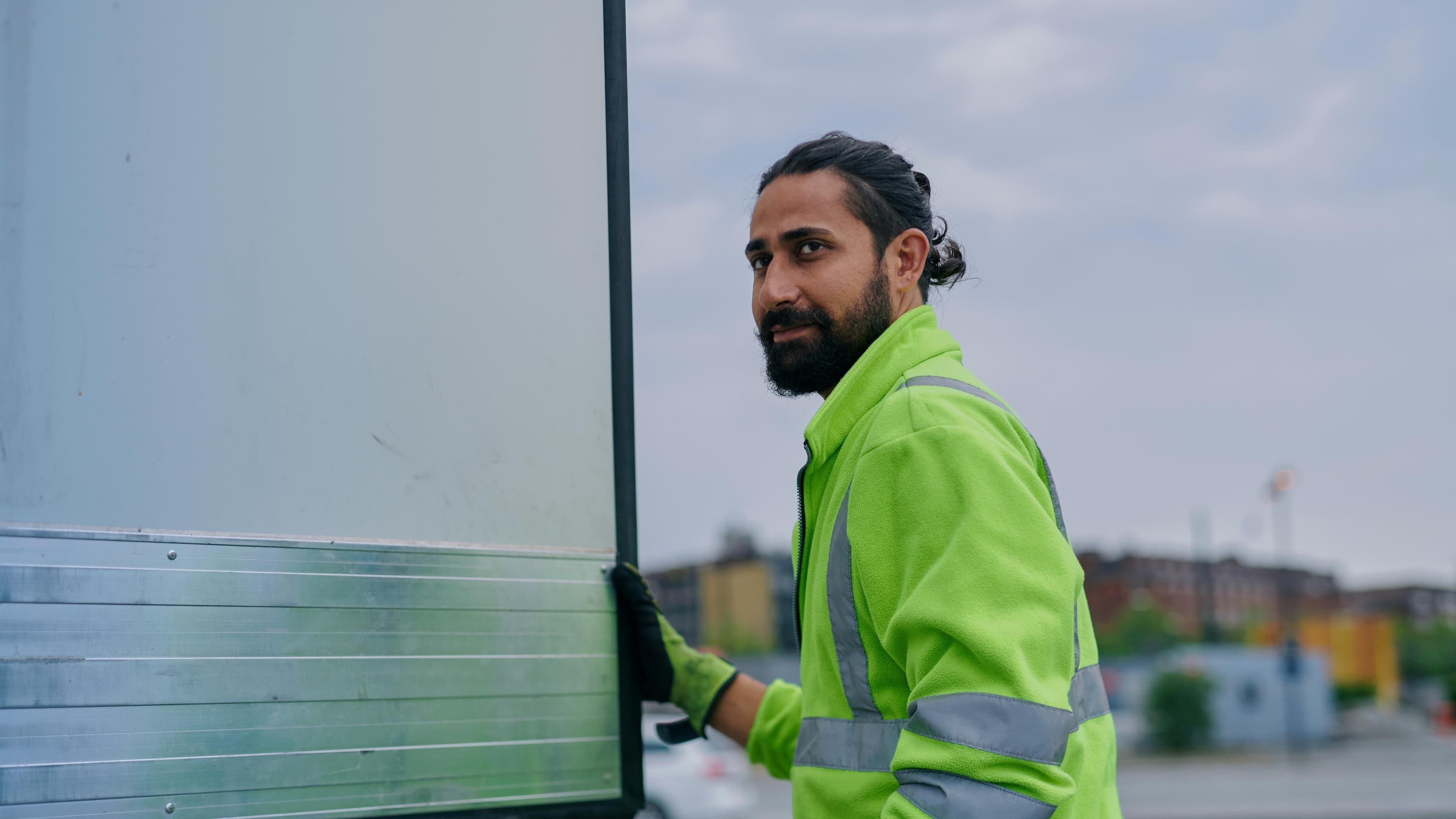 A DFDS employee wearing a high visibility jacket stands next to a trailer and looks towards his left-hand side